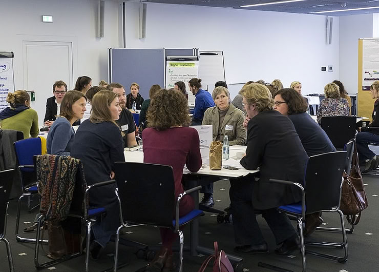 Viele Personen sitzen um Worldcafé-Tische herum
